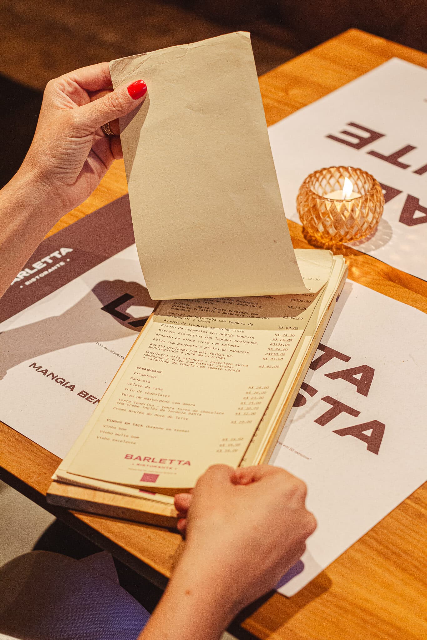 foto mostra uma pessoa sentada à mesa do barletta ristorante, abrindo o cardápio físico