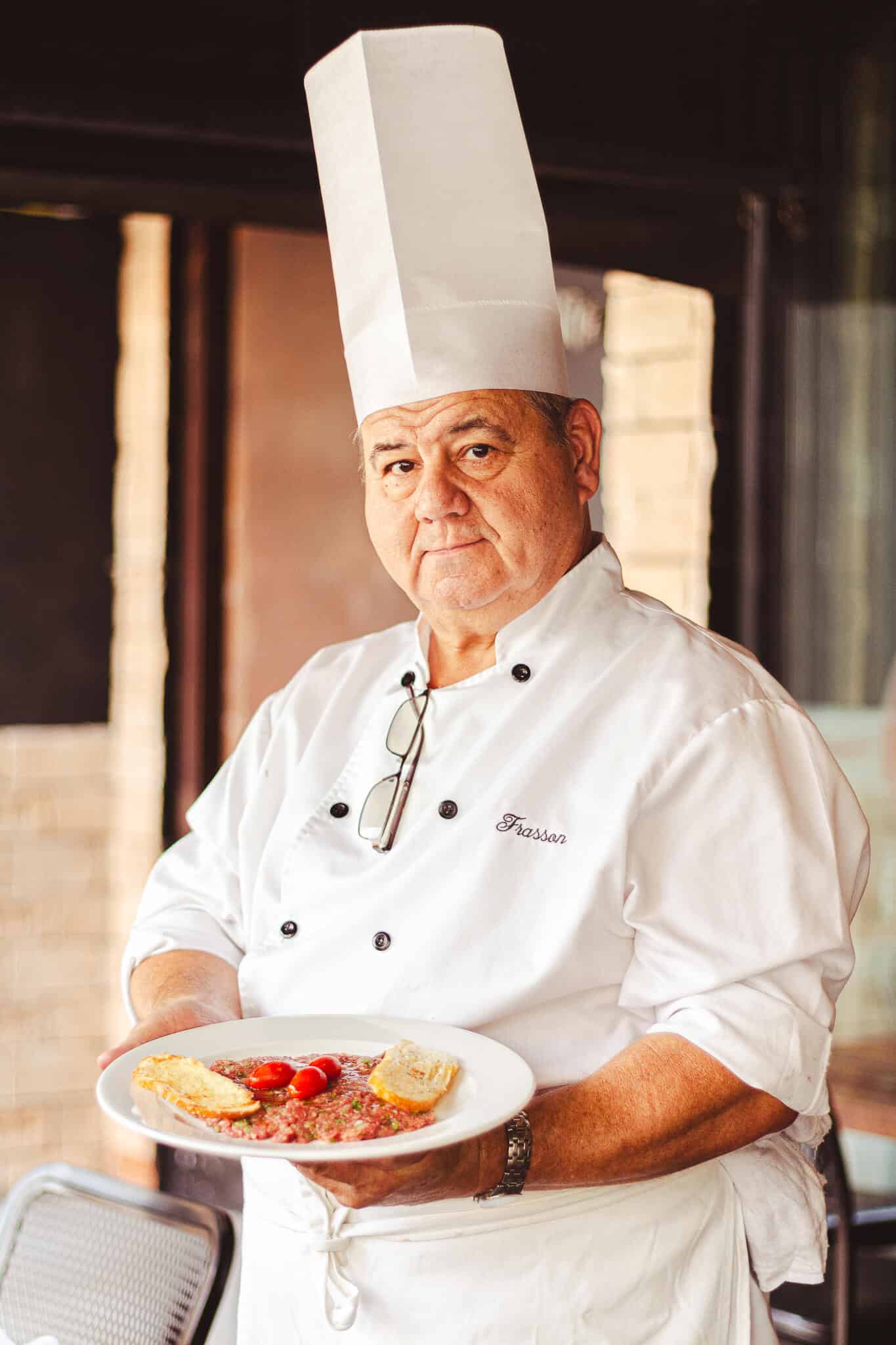 foto mostra o chef com um prato branco na mão mostrando o steak tartare feito