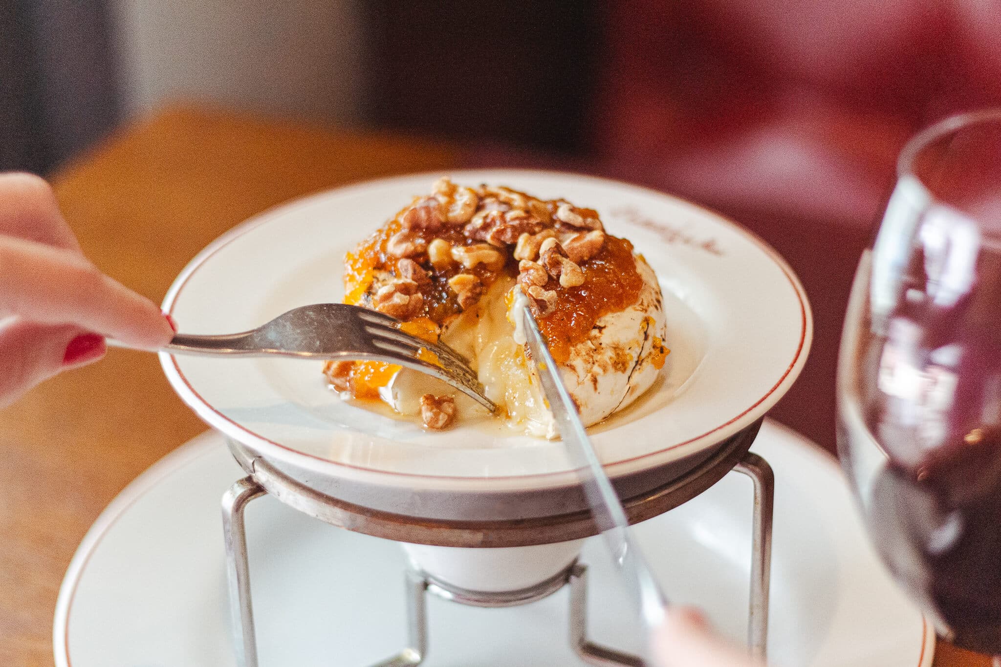 foto mostra uma pessoa cortando ao meio o quejo brie gratinado